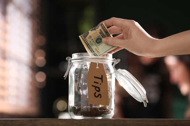 Hand placing money in tip jar